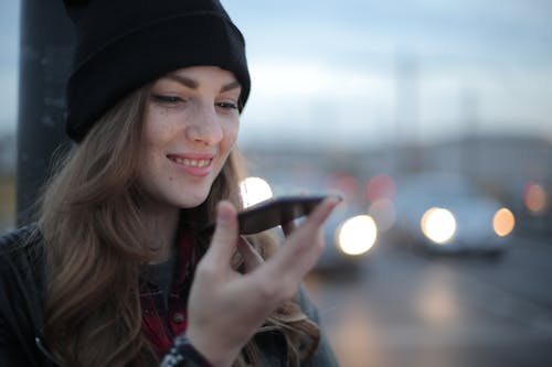 Free Joyful young woman phoning on street in evening Stock Photo