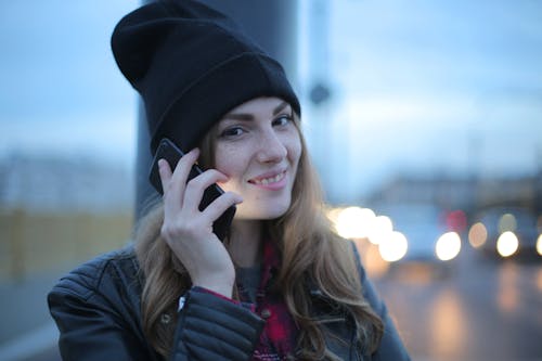 Woman in Black Knit Cap and Black Leather Jacket While Smiling