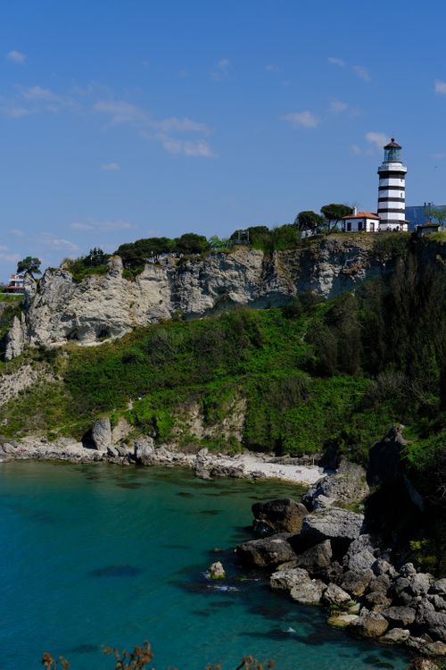 Free A picturesque view of Şile Lighthouse standing majestically on rocky cliffs by the turquoise sea under a clear blue sky. Stock Photo