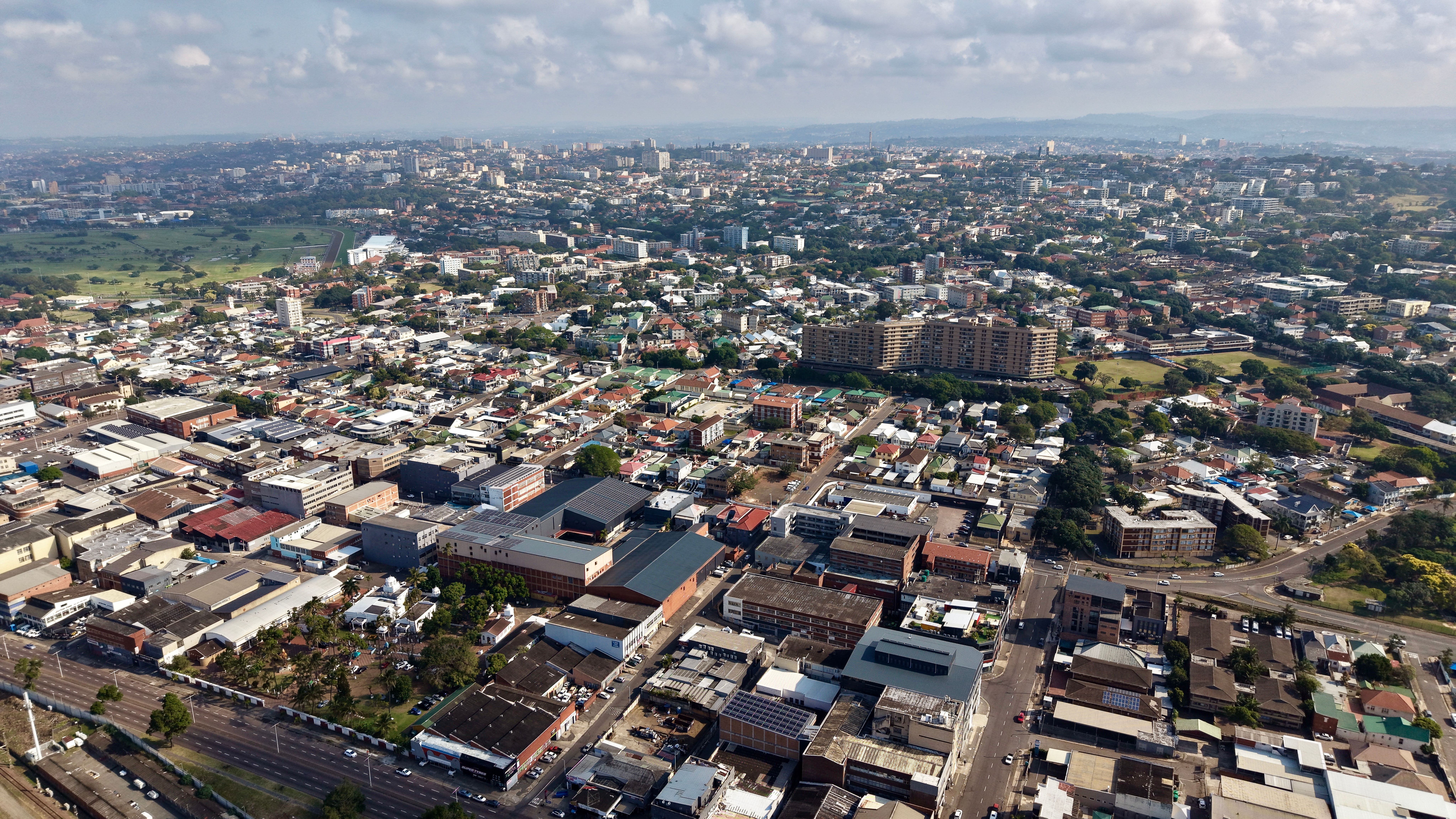 Stunning aerial view of Durban showing urban landscape, buildings, and greenery under a blue sky.