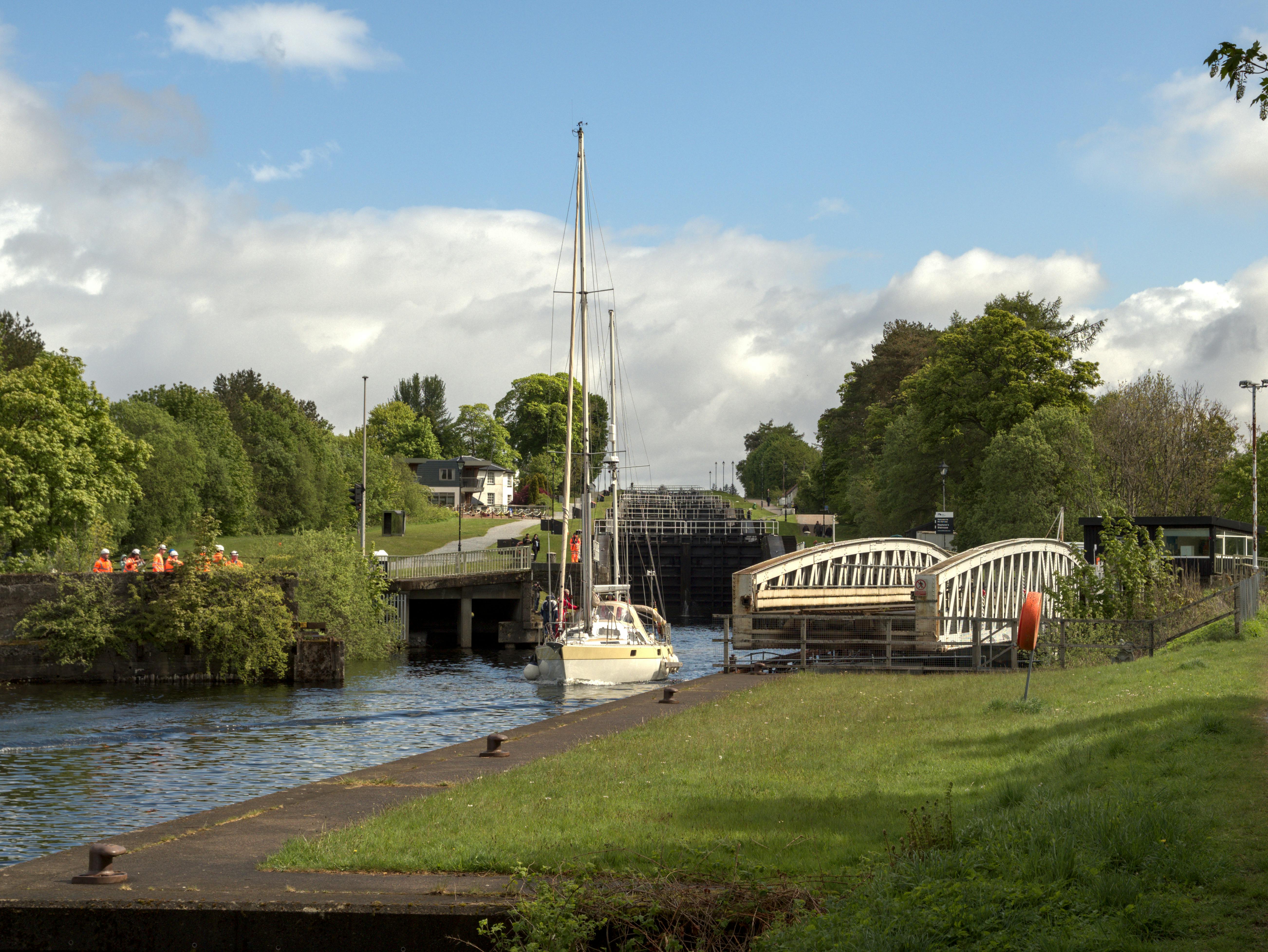 Sailboat nearing Neptune's Staircase lock system, Banavie, Scotland on a sunny day.