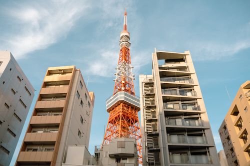 Free View of Tokyo Tower surrounded by modern apartments under a clear blue sky. Stock Photo