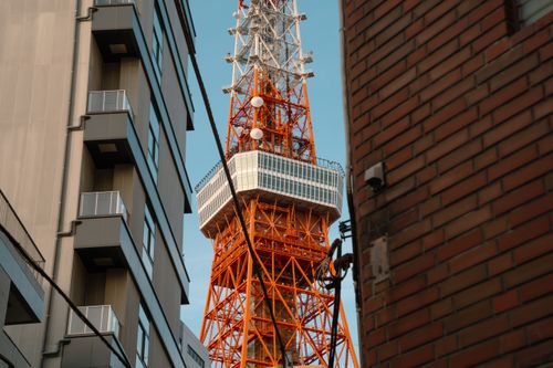 Free A glimpse of the iconic Tokyo Tower, framed by city buildings under a clear sky. Stock Photo