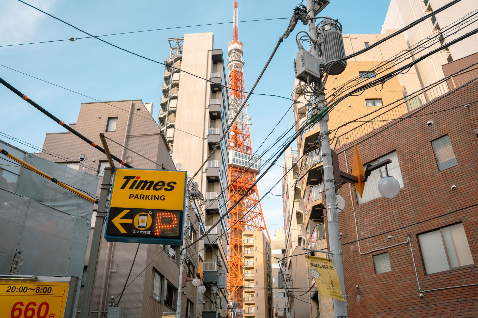 A vibrant street scene featuring the iconic Tokyo Tower surrounded by urban architecture and power lines.