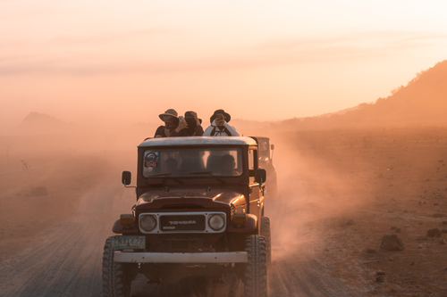 Free A Jeep navigates dusty roads during sunrise in Botolan, Philippines, capturing adventure and exploration. Stock Photo