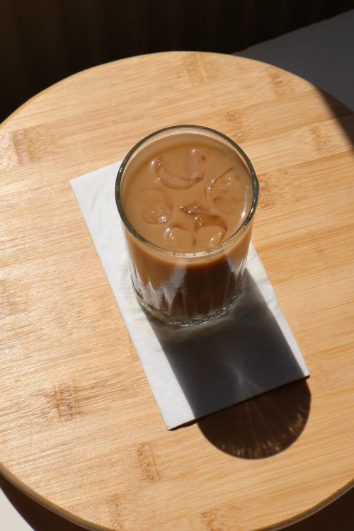 Free A top-down view of refreshing iced coffee in glass on a wooden table with shadow play. Stock Photo