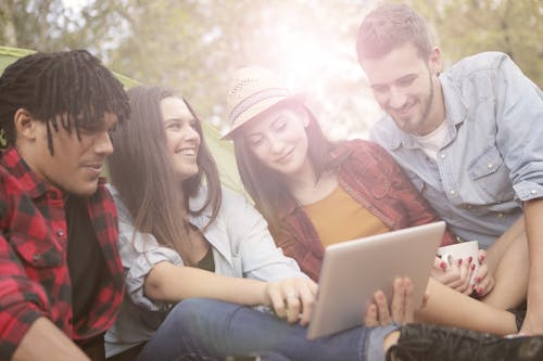 Cheerful friends browsing laptop in forest