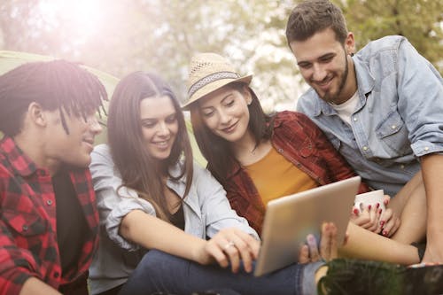 Cheerful woman showing friends funny video on tablet