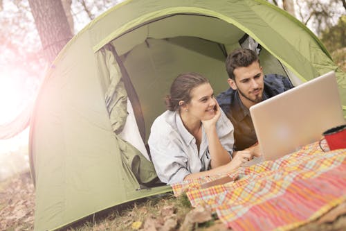 Free Happy couple using laptop in tent Stock Photo