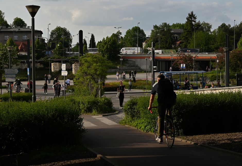 A cyclist rides through a busy street in Krakow, Poland, on a summer day.