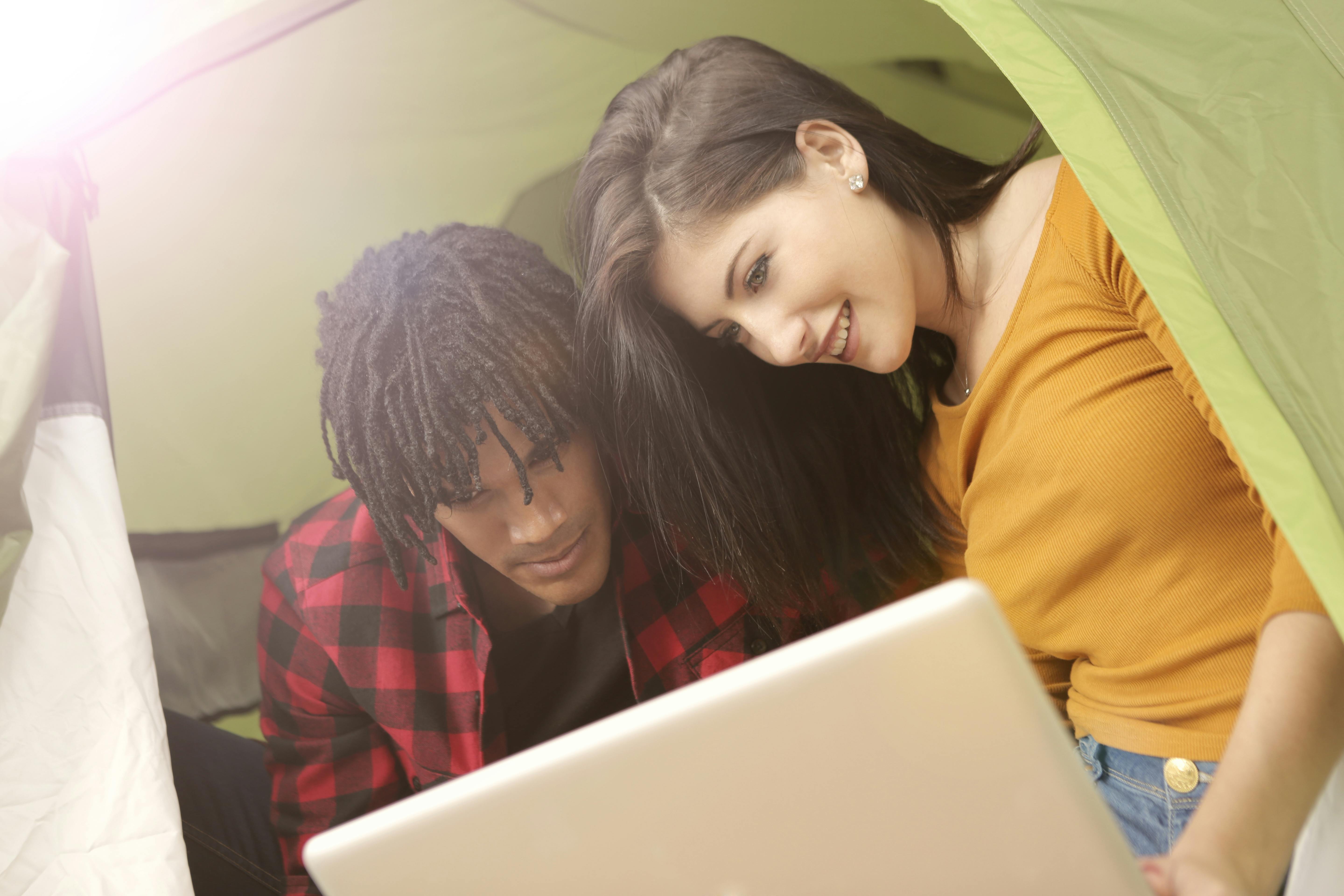 a photo of a couple inside fabric shelter using computer laptop