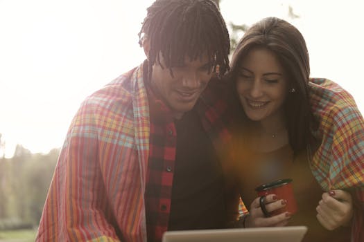 一对夫妇裹着毯子，在户外面带微笑地享受咖啡