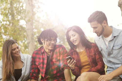 Woman in Plaid Long Sleeve Showing Photos on Her Smartphone