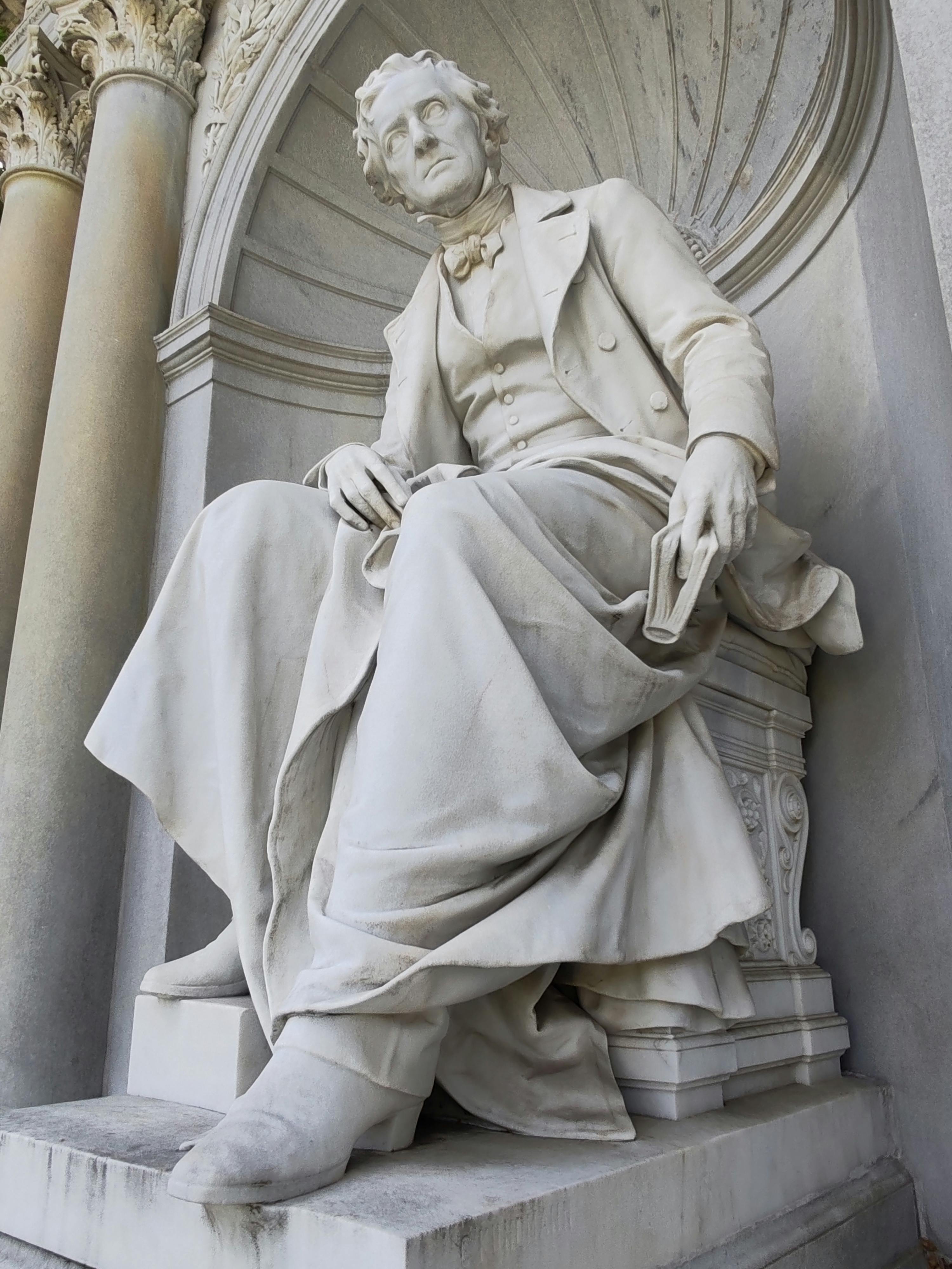 A detailed marble statue of a historical figure seated with grand architectural elements.