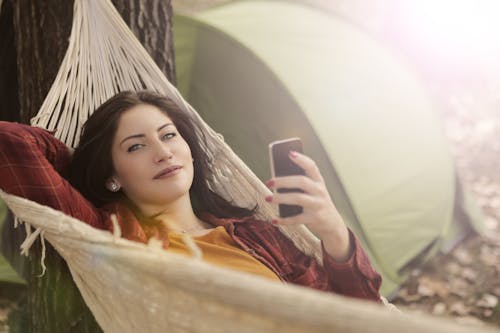 Free Woman Lying on Hammock While Using Cellphone Stock Photo