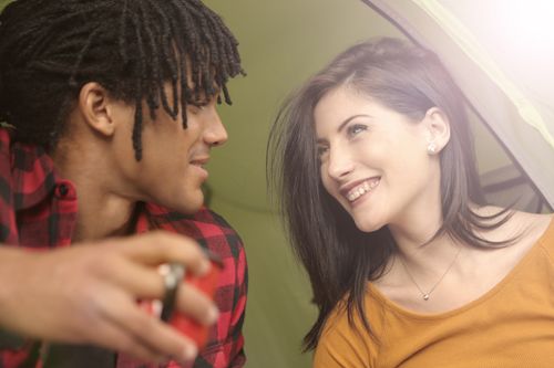 Free Happy multiethnic woman and man talking and looking at each other while sitting with cup of tea in tent Stock Photo