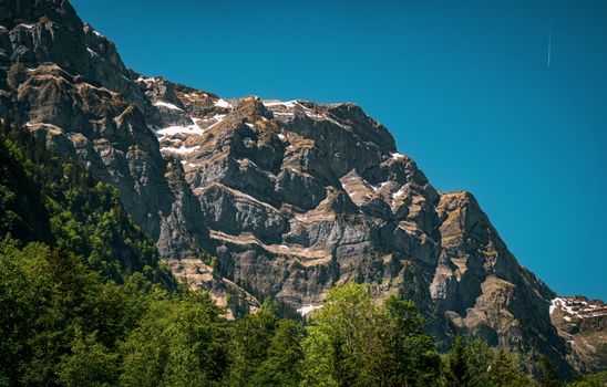A stunning scene of the Glarus Alps in Switzerland showcasing rocky peaks and lush greenery.