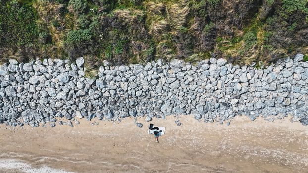 Aerial shot of a rocky beach in County Dublin, Ireland, with a lone visitor and lush greenery.