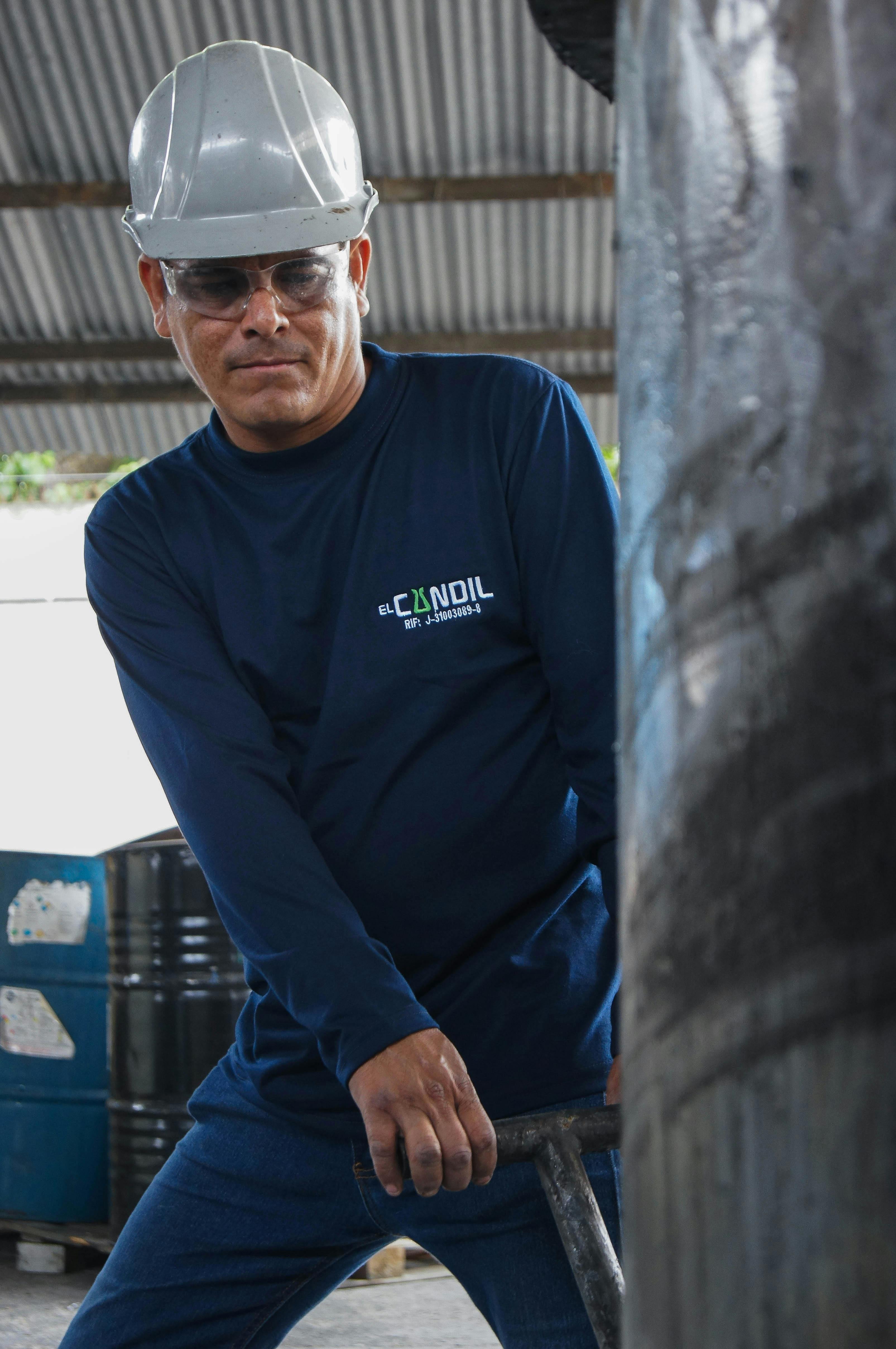 An industrial worker wearing protective gear operates machinery inside a factory.