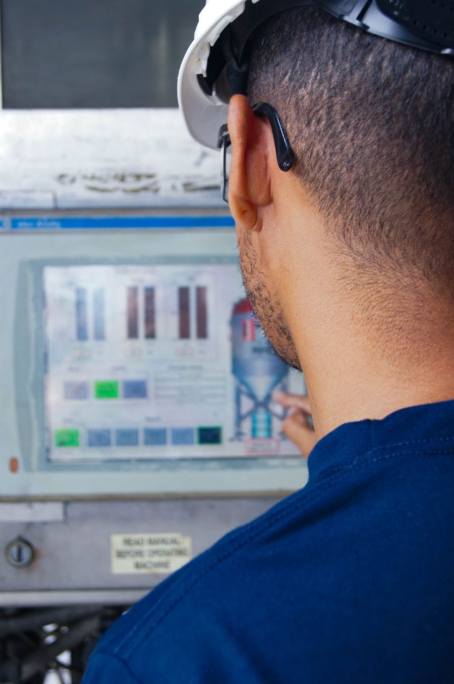 Engineer working at an industrial control panel with HMI graph display