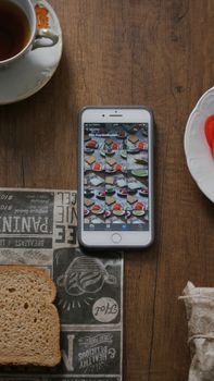 Flat lay of breakfast items with smartphone showing photo gallery on a wooden table, evoking a cozy atmosphere.