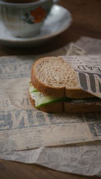 Delicious sandwich wrapped in paper beside a coffee cup, showcasing a cozy setting.