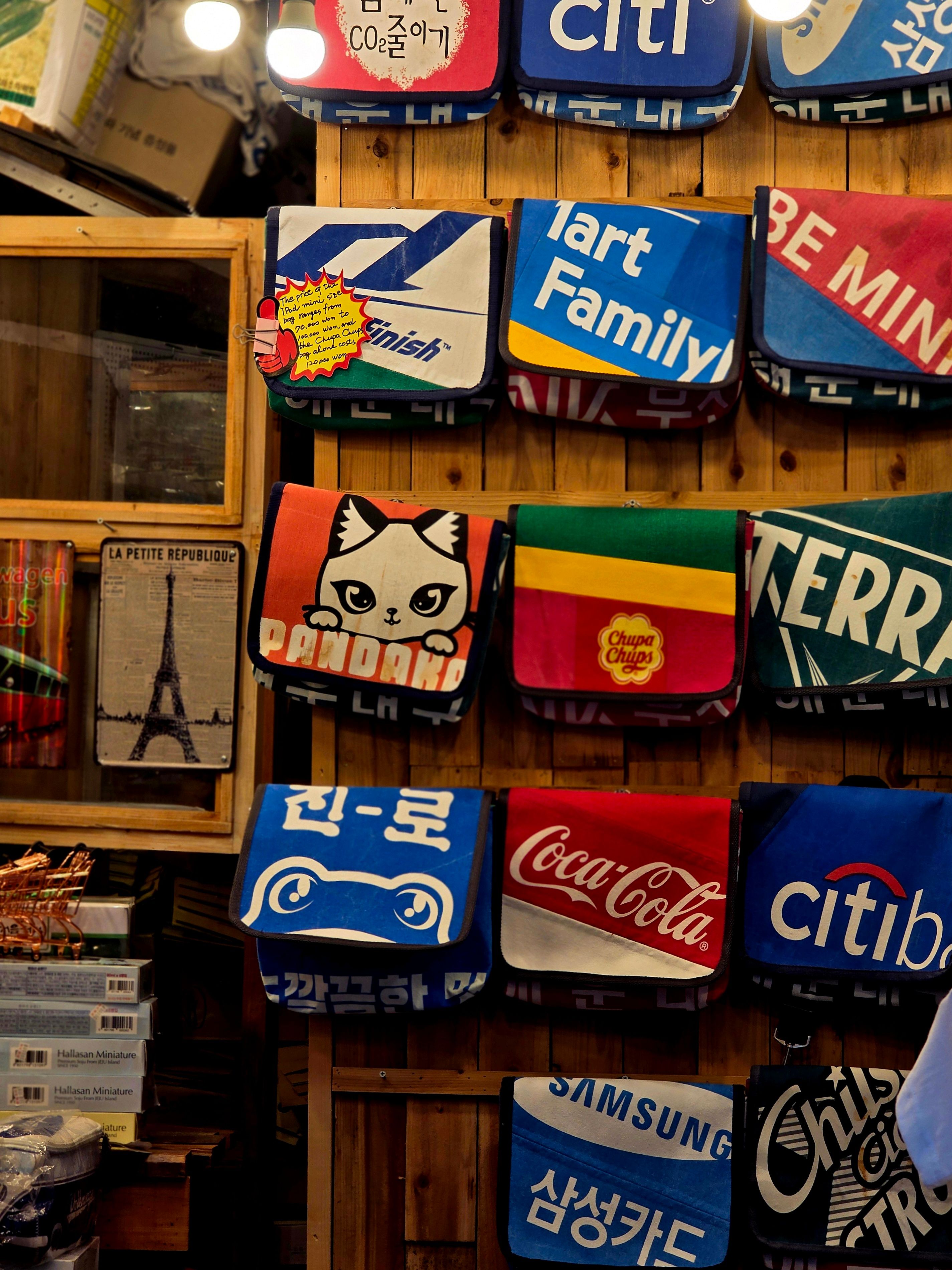 Vibrant display of novelty bags with logos and designs at a market in Busan, South Korea.