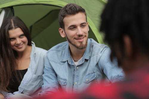 Happy couple sitting in front of tent