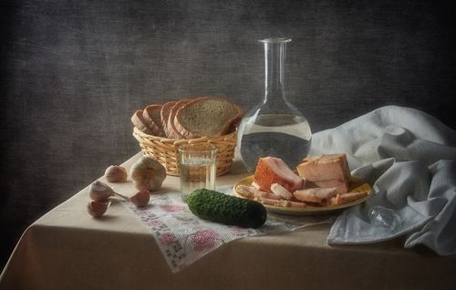 Free A rustic still life composition featuring bread, salo, garlic, and water on a linen tablecloth. Stock Photo