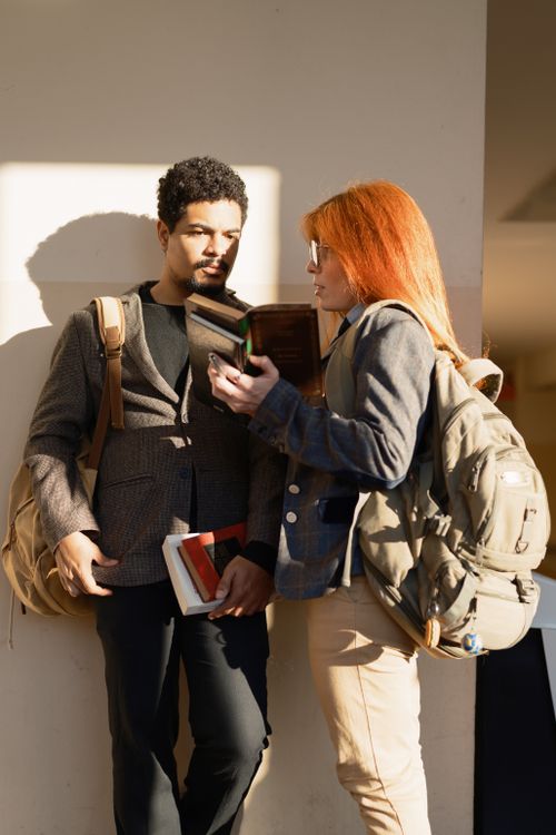 Free Two students with backpacks and books discussing under sunlight on Buenos Aires campus. Stock Photo