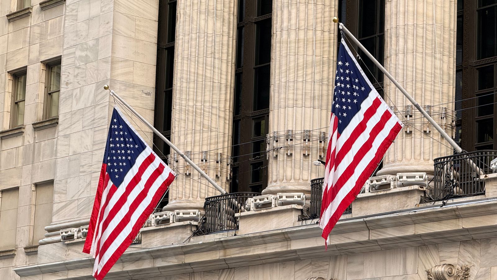 American flags displayed prominently on a historic Wall Street building in New York City.