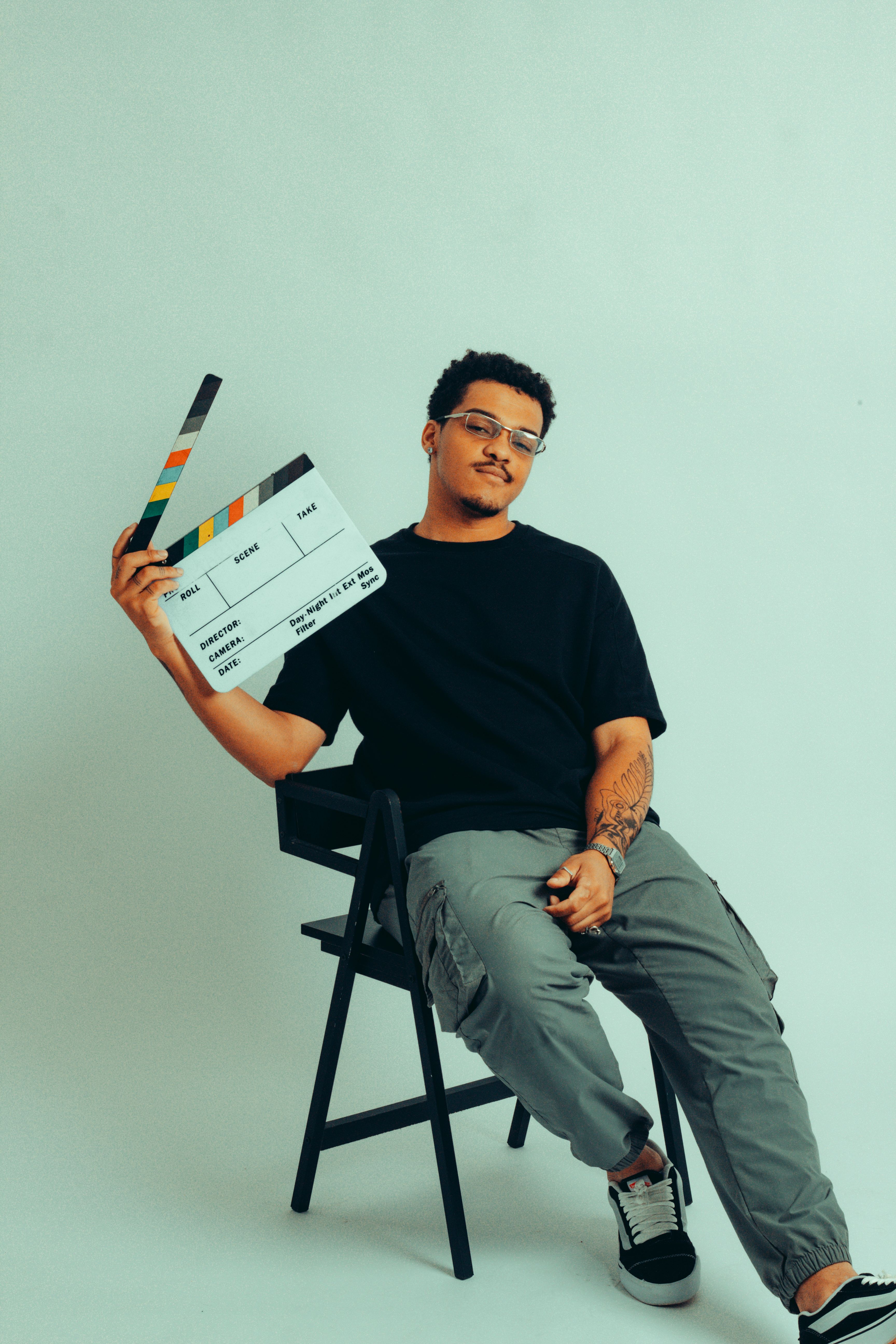 Portrait of a young filmmaker holding a clapperboard in a modern studio setting.