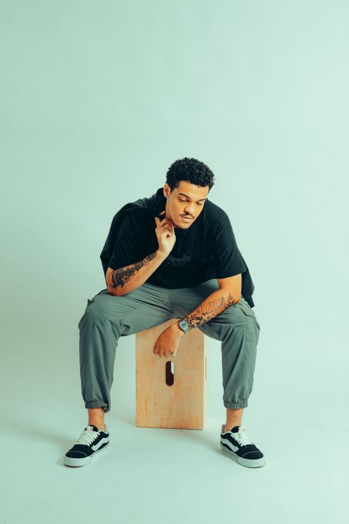 Free Stylish young adult with tattoos sitting thoughtfully on a wooden block. Stock Photo