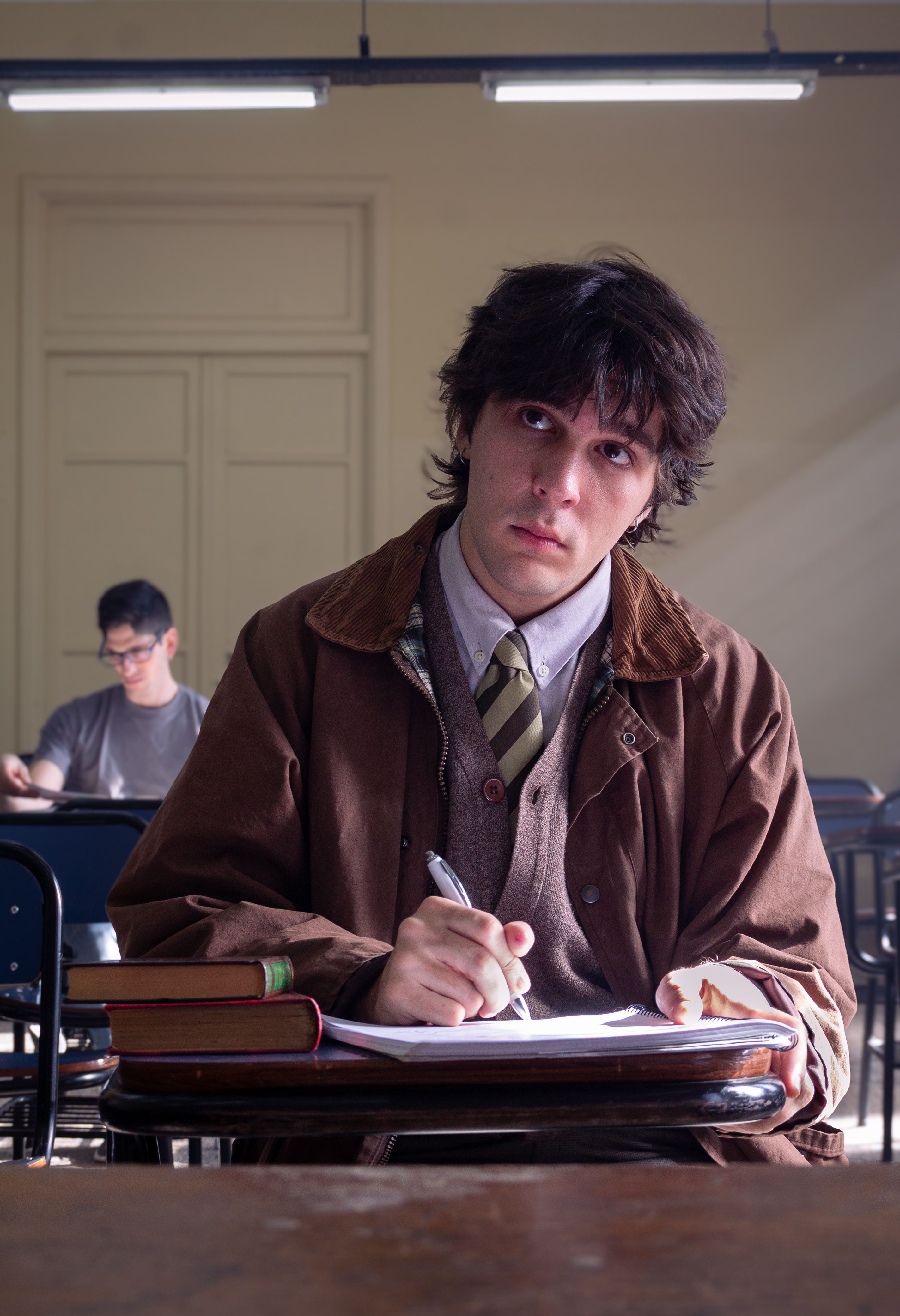 Young man with books in a Buenos Aires classroom, focused and studying.
