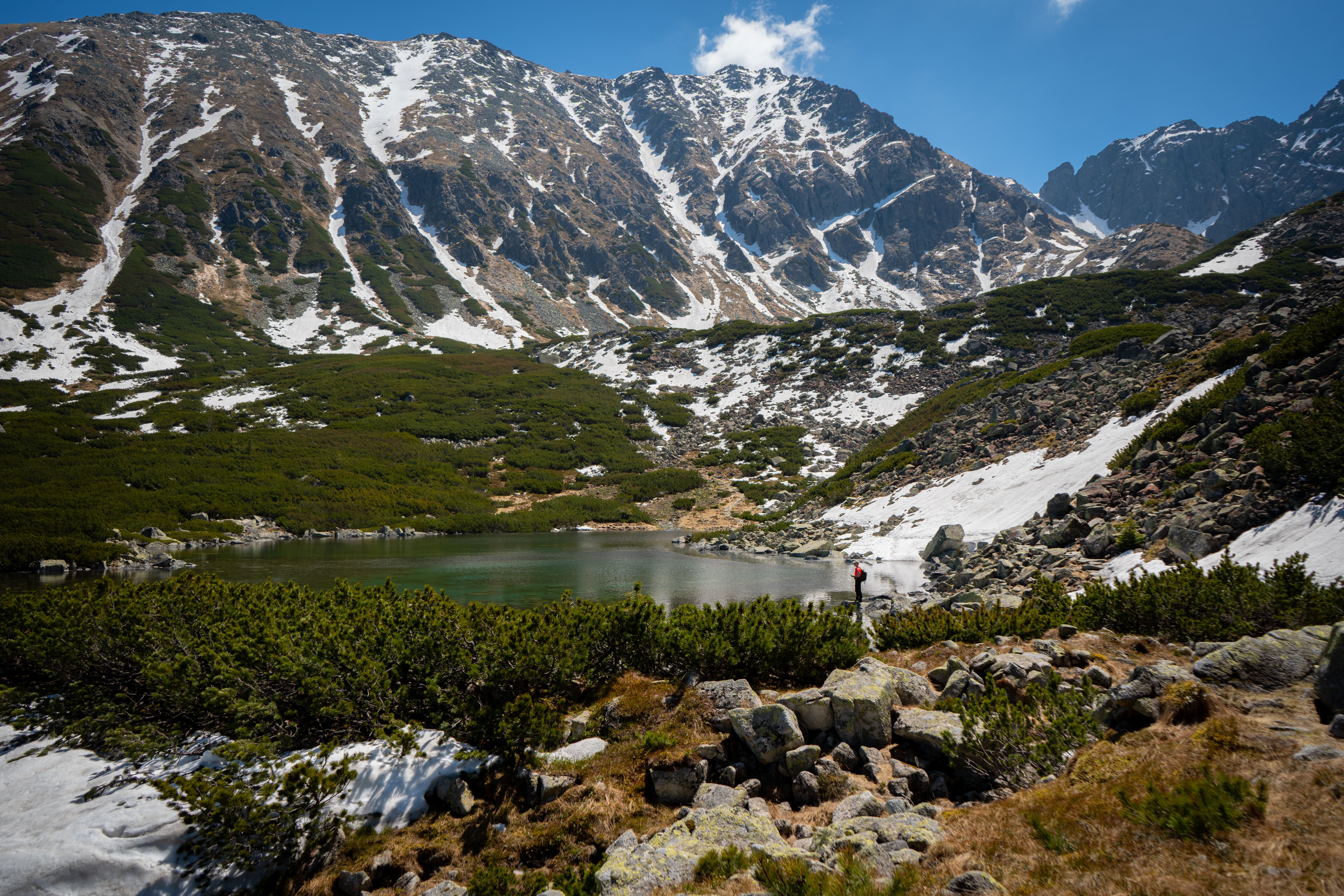 Breathtaking view of a mountain range with snow patches and a tranquil lake, perfect for adventure and travel enthusiasts.