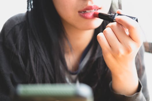 Close-up of a woman applying lipstick, focusing on lips and hands. Perfect for beauty and makeup themes.