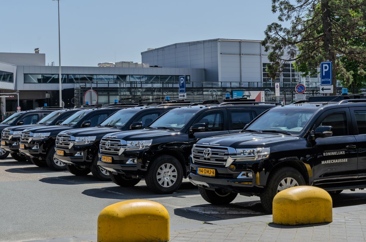 Vehicles lined up at an airport parking area under a cloudy sky