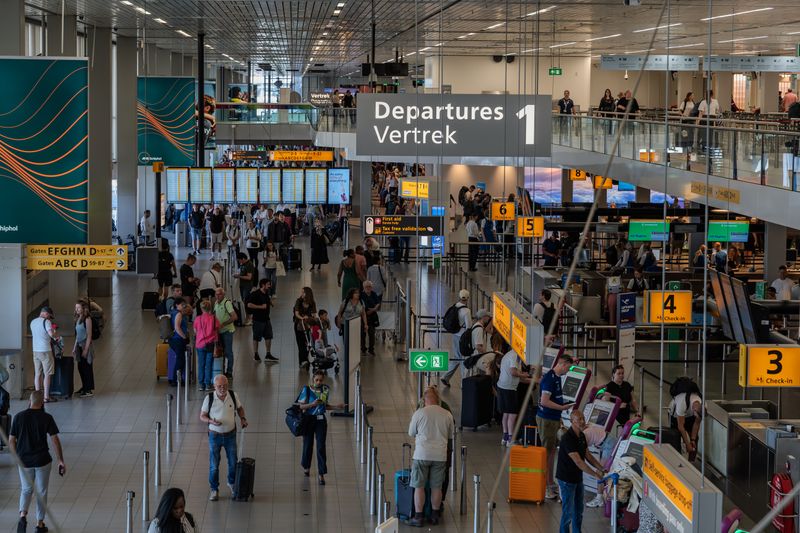 Crowds in the departure area of Amsterdam's Schiphol Airport, showcasing bustling travel activity.