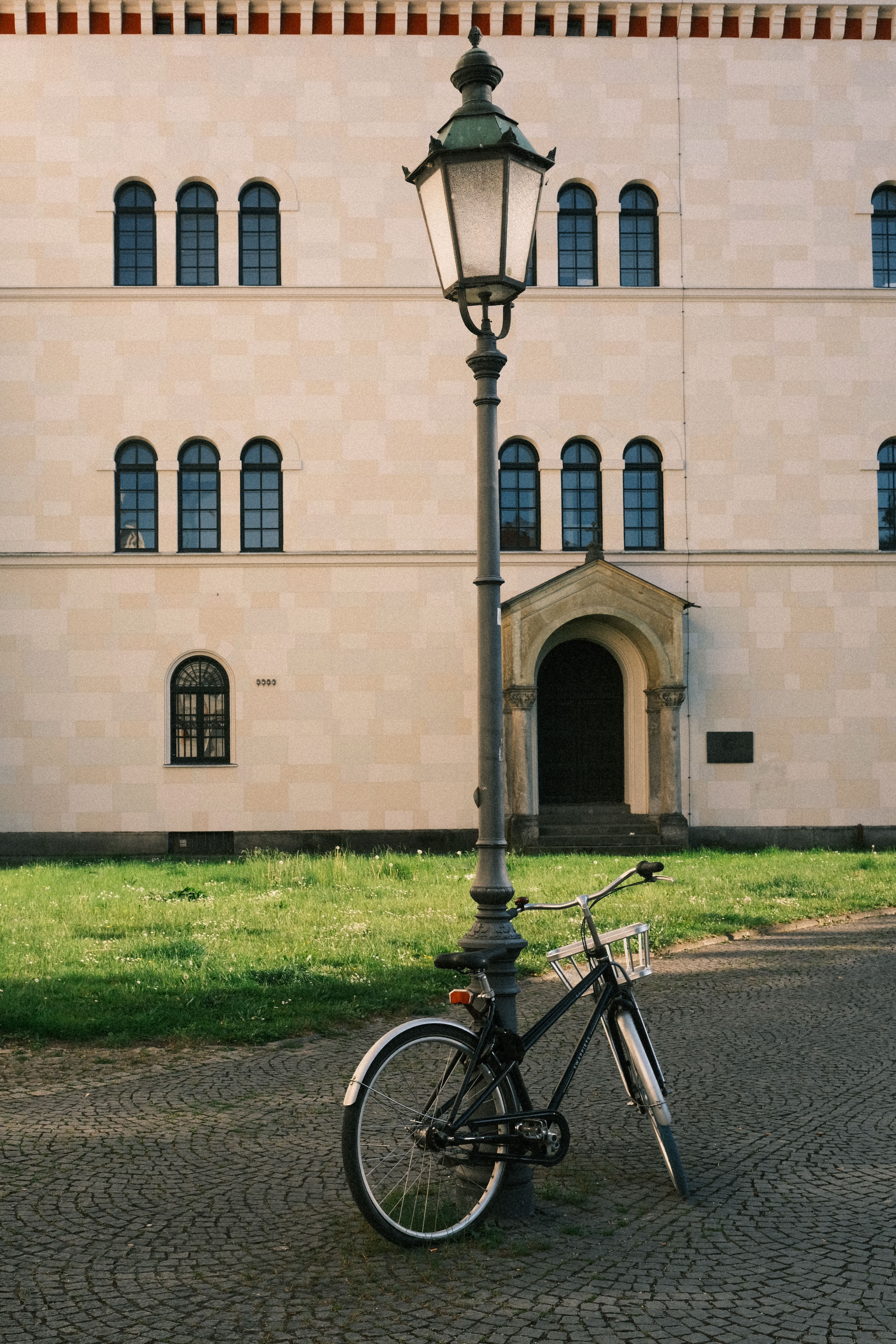A classic bicycle parked under a vintage street lamp against a historic building in Munich.