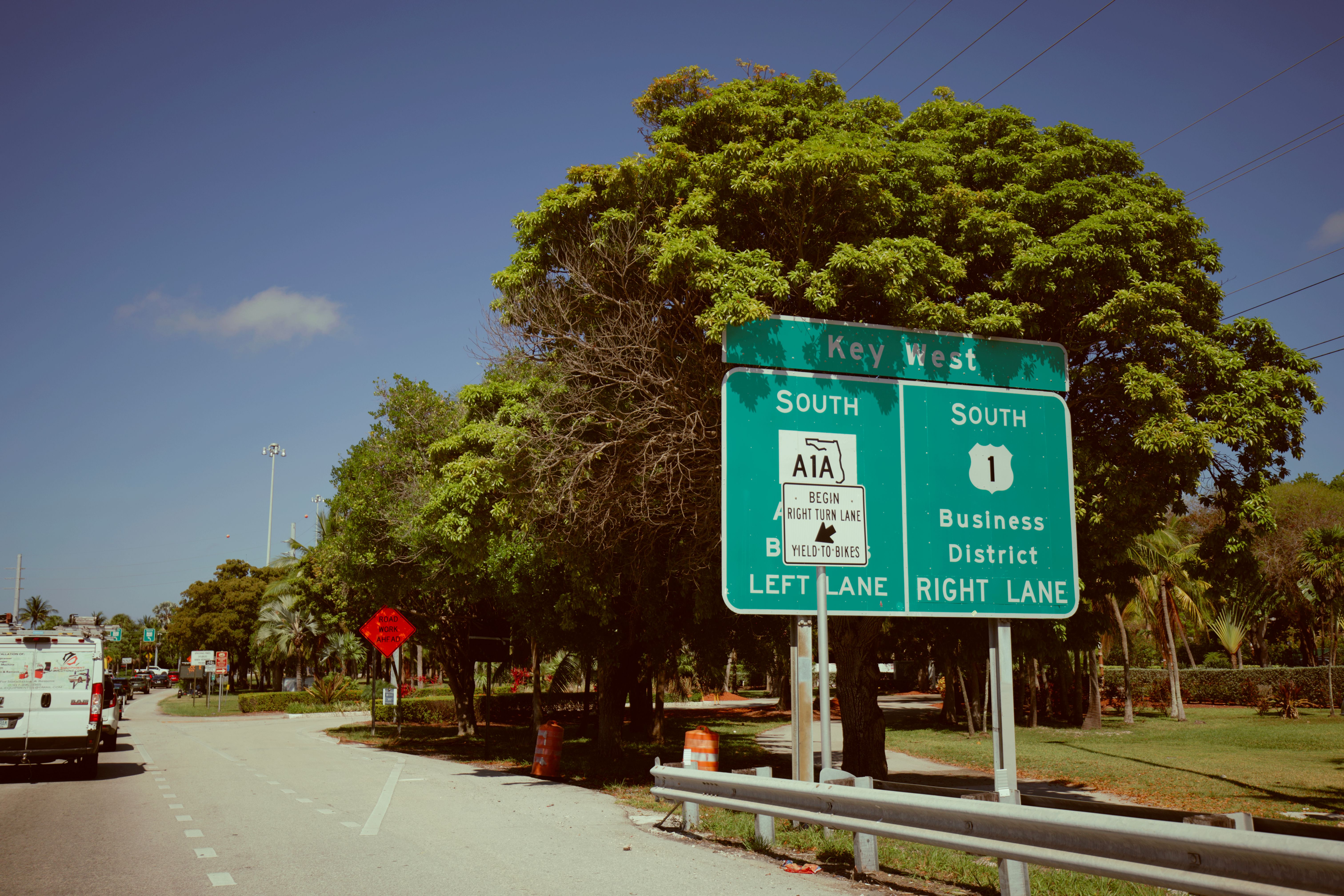 Directional sign for Key West, Florida on a clear day. Green road signs guide travelers southwards.