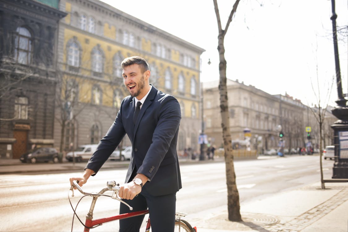 빨간 자전거를 타는 동안 검은 양복 재킷과 검은 바지를 입은 남자