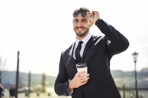 Man in Black Suit Holding White Cup