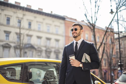 Man in Black Suit Standing Beside Yellow Car