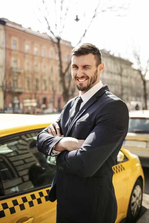 Man in Black Suit Standing Near Yellow Cab