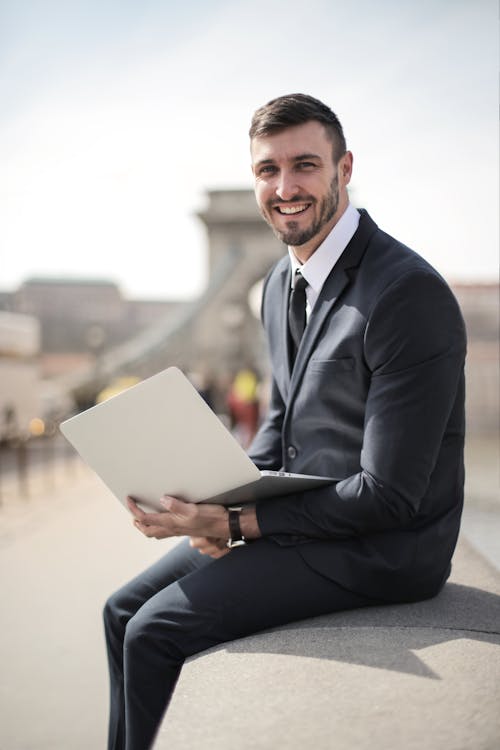 Man in Black Suit Jacket Holding Silver Laptop Computer