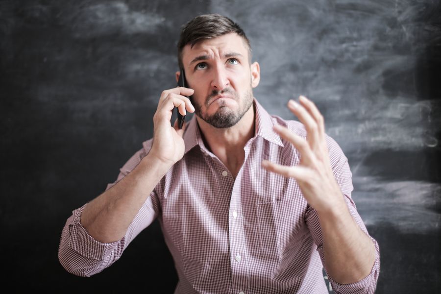 A frustrated man gesturing while on a phone call, conveying the stress of being locked out of an account