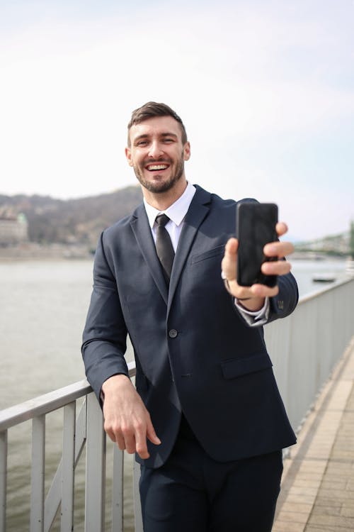 Homem De Paletó Preto Segurando Um Smartphone Preto