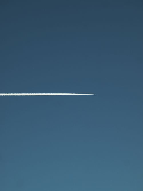 Free A jet airplane leaves a long contrail across a clear blue sky, symbolizing travel and freedom. Stock Photo