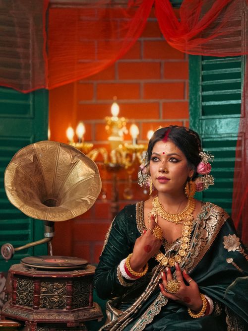 Woman in ornate occasion wear beside a vintage gramophone