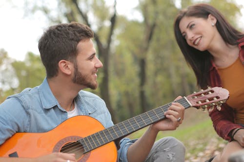 Photo of Man Playing Guitar Beside a Woman